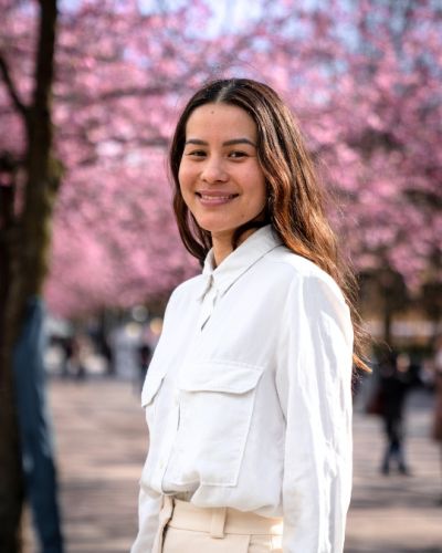 Profile image of Tatiana Hariki in a white shirt with cherry tree blossoms in the background.