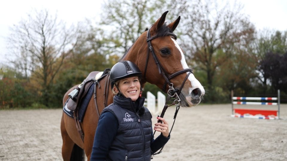 Profile image of Meredith Michaels Beerbaum holding a tacked up young horse.